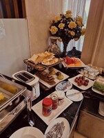 Un bufé de desayuno con diferentes opciones de comida, un tostador y un jarrón con flores amarillas.