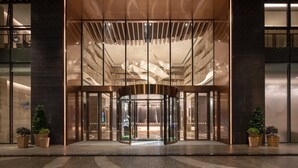 A modern building entrance with a revolving door, large glass panels, and potted plants. - Holiday Inn Foshan Shunde (Foshan)
