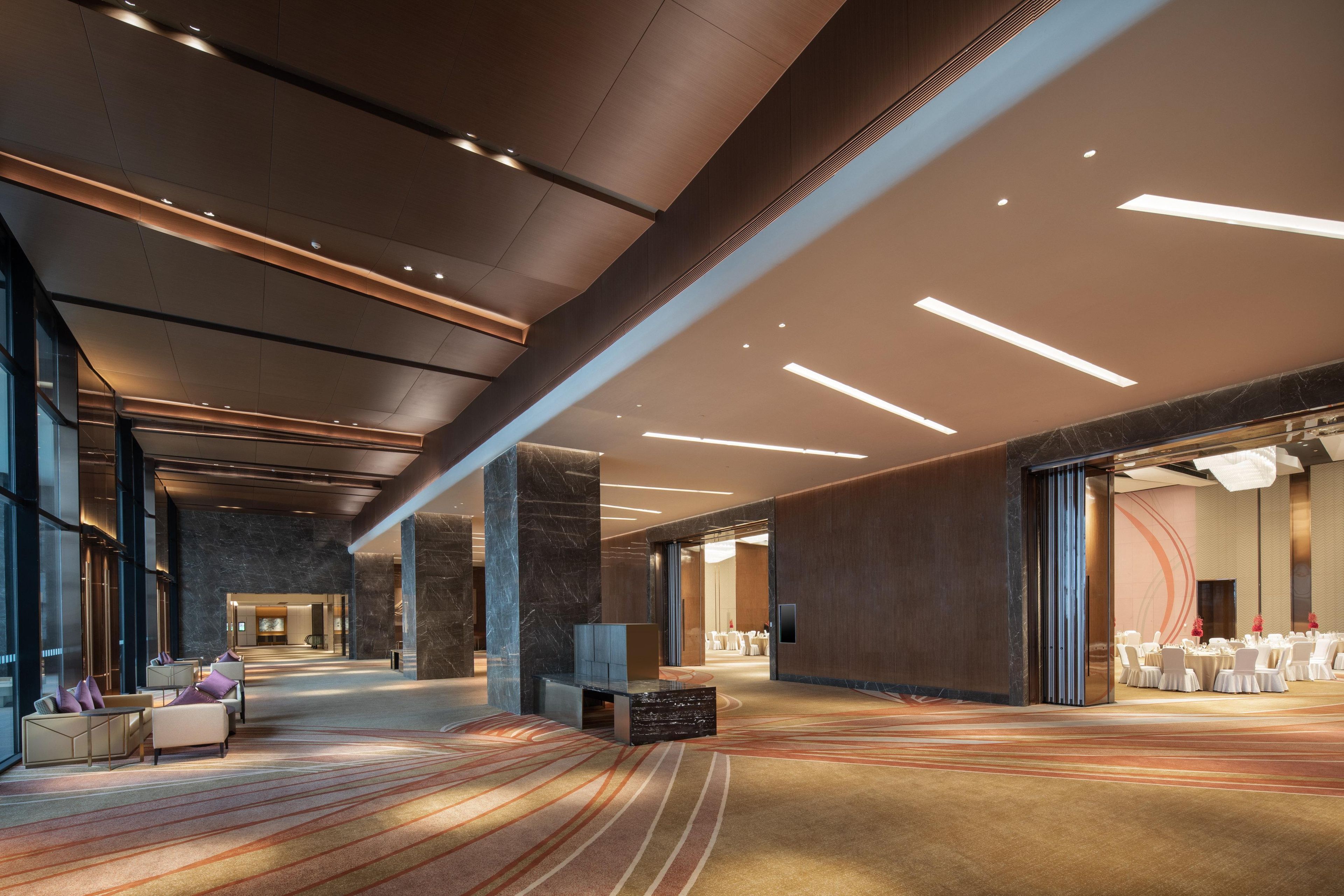 Un hall d’entrée spacieux, doté d’un sol en marbre, d’un espace salon et offrant une vue sur une salle de réception.