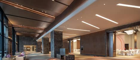 Un hall d’entrée spacieux, doté d’un sol en marbre, d’un espace salon et offrant une vue sur une salle de réception.