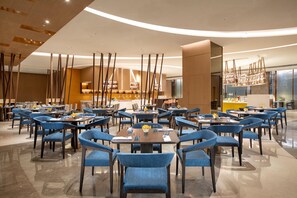 A spacious dining area with multiple tables and chairs, a central bar, and a modern ceiling design. - Holiday Inn Foshan Shunde (Foshan)