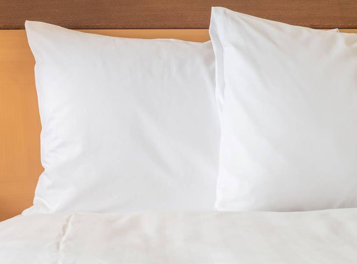 A bed with white bedding and a wooden headboard.