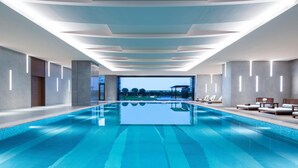 Piscina interior moderna com vista clara do céu e área de estar à beira da piscina.