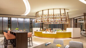 A modern hotel lobby with a central bar area, seating arrangements, and a decorative ceiling light fixture. - Holiday Inn Foshan Shunde (Foshan)