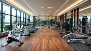 A gym with exercise equipment, large windows, and a wooden floor. - Holiday Inn Foshan Shunde (Foshan)