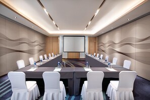 A conference room with a long table, white chairs, and a projector screen. - Holiday Inn Foshan Shunde (Foshan)
