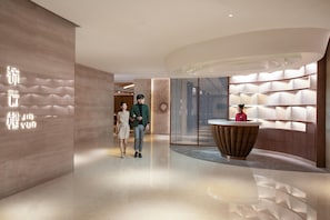 A modern hotel lobby with a reception desk, a large wall with a geometric pattern, and a polished floor. - Holiday Inn Foshan Shunde (Foshan)