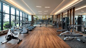 Uma academia com equipamentos de ginástica, amplas janelas e piso de madeira.