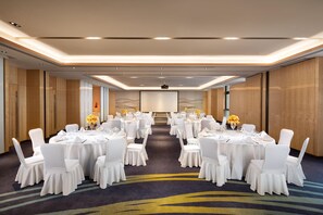 A conference room with multiple tables and chairs, a projector screen, and a carpeted floor. - Holiday Inn Foshan Shunde (Foshan)