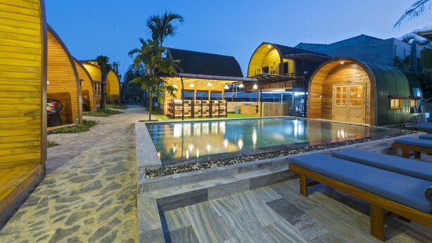 A resort with wooden cabins, a swimming pool, and lounge areas. - CoCo Farm Hoi An (Da Nang)
