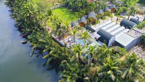 A tropical resort with a pool, palm trees, and bungalow-style accommodations. - CoCo Farm Hoi An (Da Nang)