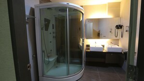Une salle de bain moderne avec une douche à parois de verre, un lavabo et un miroir.