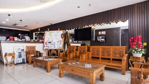 Un hall d’hôtel comprenant un comptoir d’accueil, des meubles en bois, un téléviseur à écran plat et un mur décoratif.
