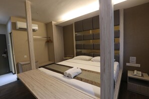 A modern hotel room with a large bed, wooden headboard, and a bedside table with a phone.