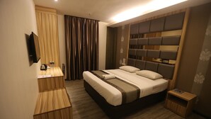Une chambre d’hôtel moderne dotée d’un grand lit, d’un bureau en bois, d’une télévision à écran plat et d’une petite table de chevet.