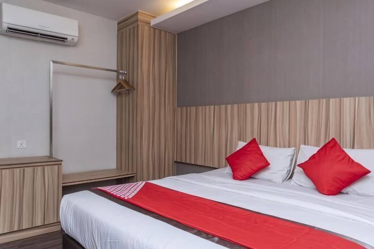 Quarto de hotel com cama, guarda-roupa, espelho e ar condicionado.