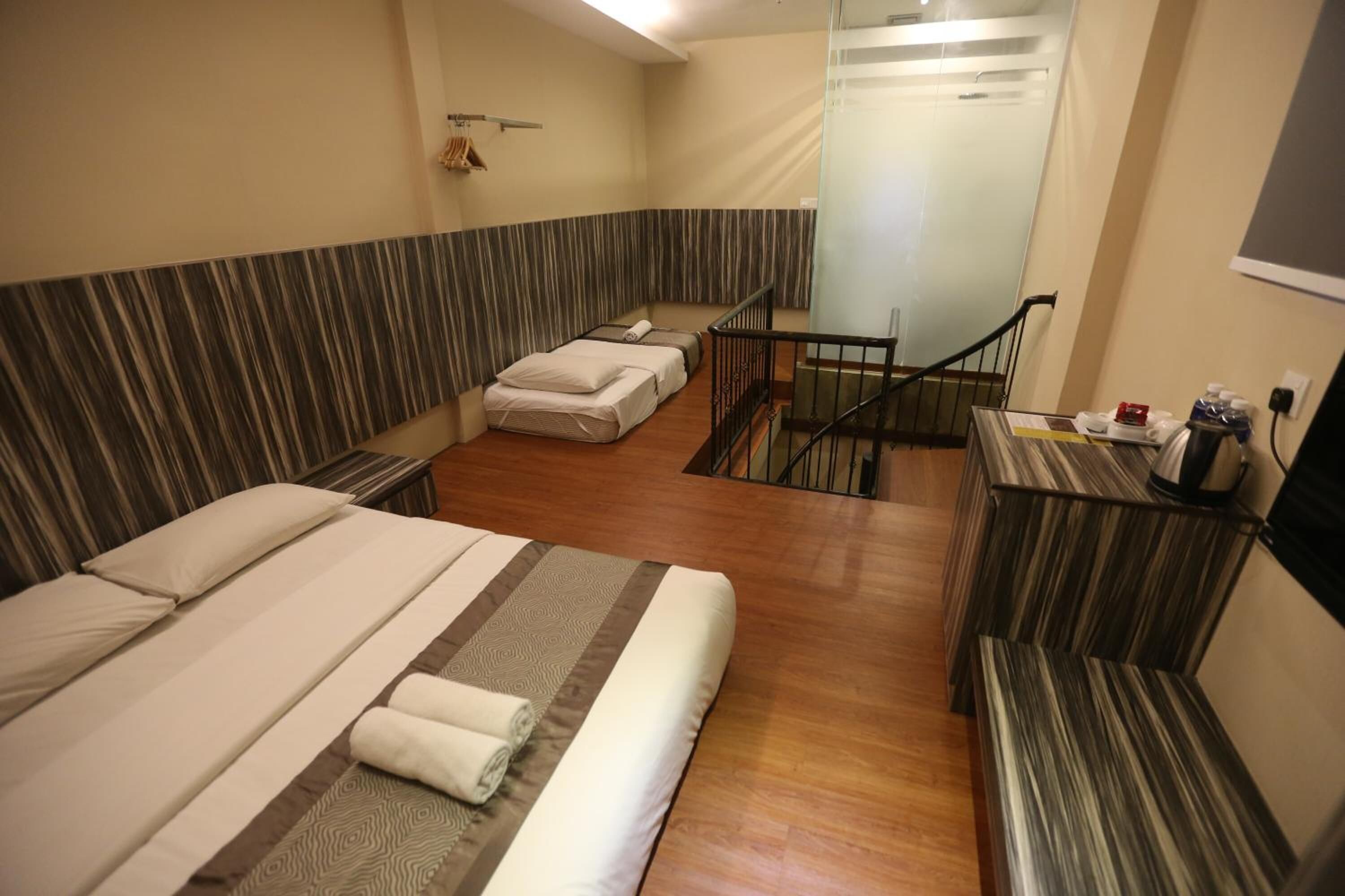 Ein Hotelzimmer mit zwei Betten, Holzboden, einem kleinen Schreibtisch mit Stuhl und einer Treppe.