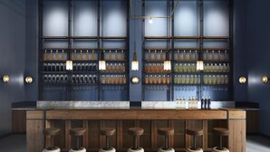 A bar area with a wooden counter, multiple shelves of bottles, and three stools. - Ultimate Provence Hotel & Spa Golfe de Saint Tropez (La Garde-Freinet)