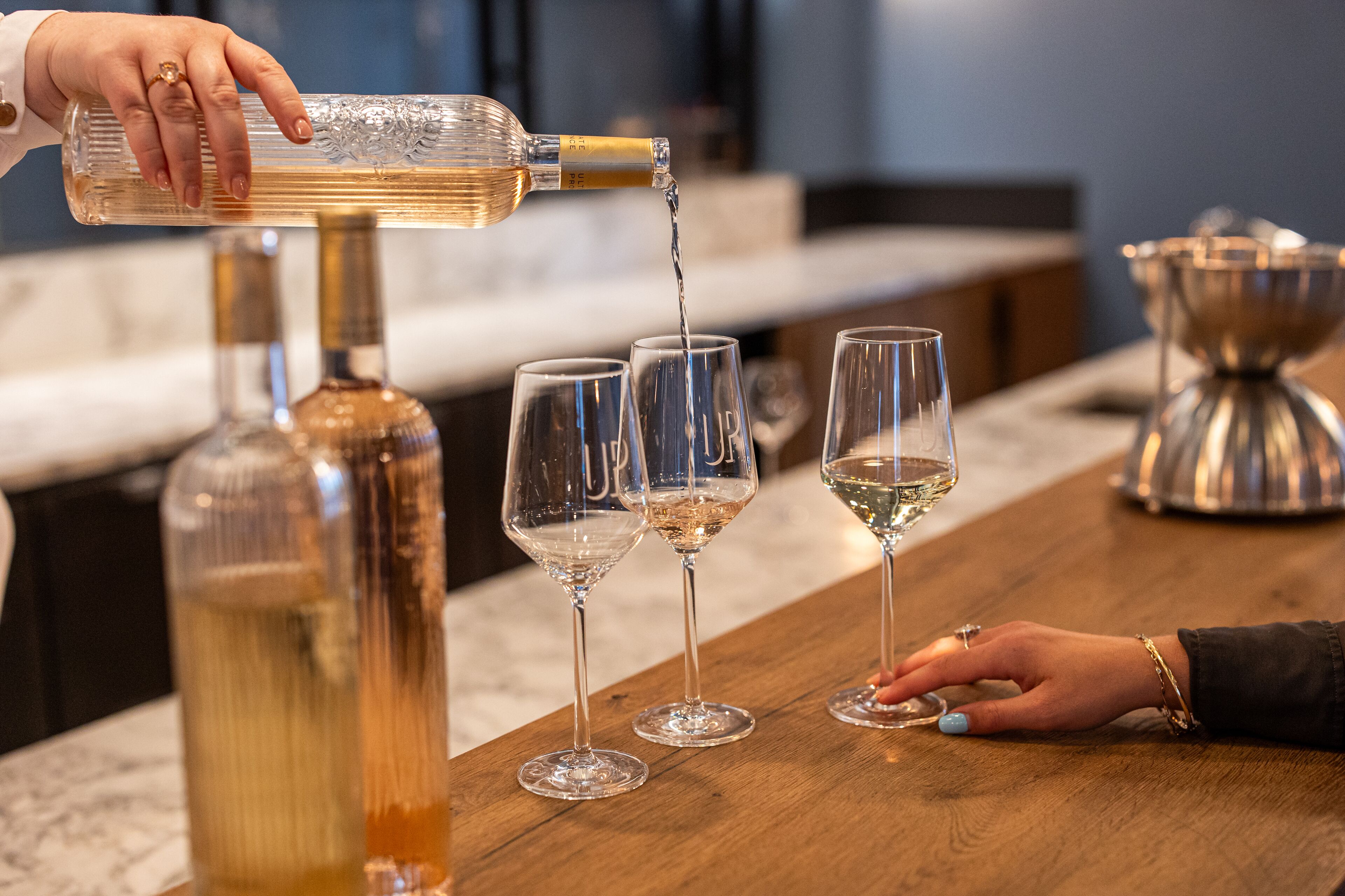 A bar setting with a bottle being poured into glasses.