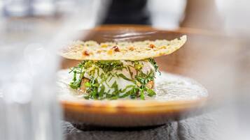 A close-up of a dish with a crispy edge, garnished with herbs, on a round plate.