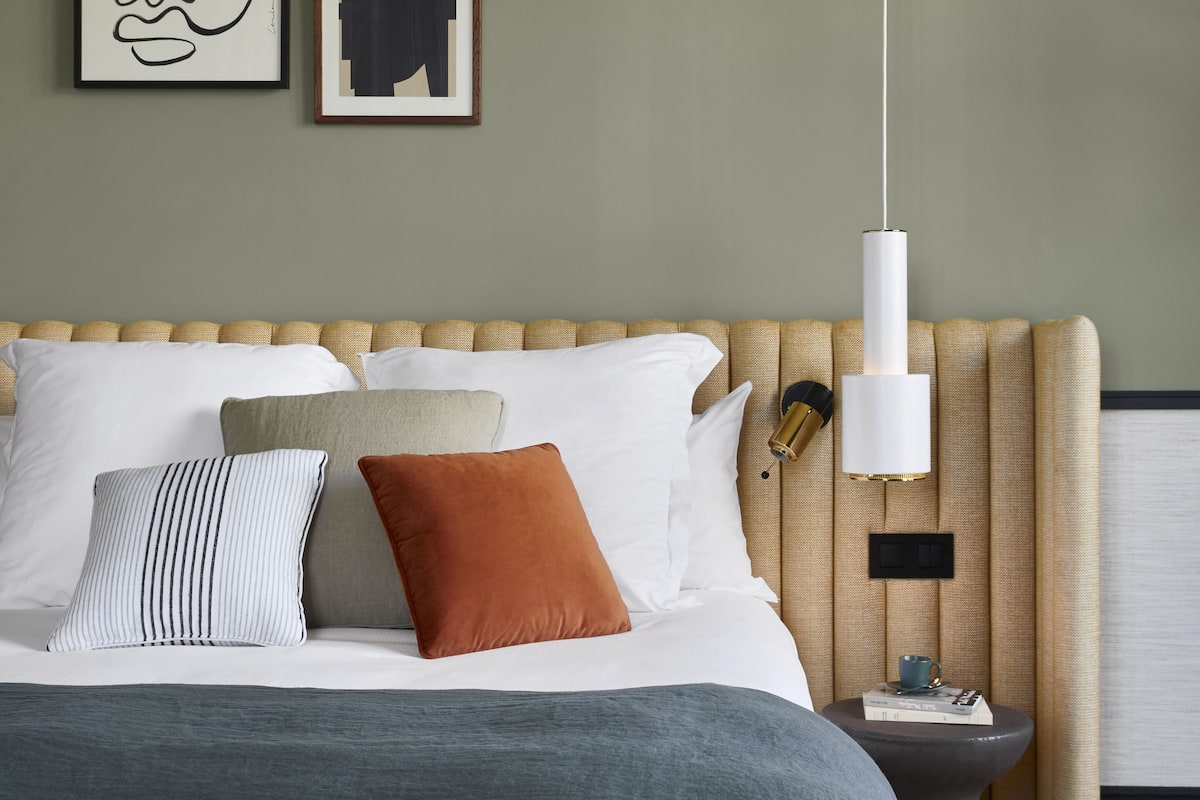 A neatly made bed with a variety of pillows and a bedside table with a lamp.