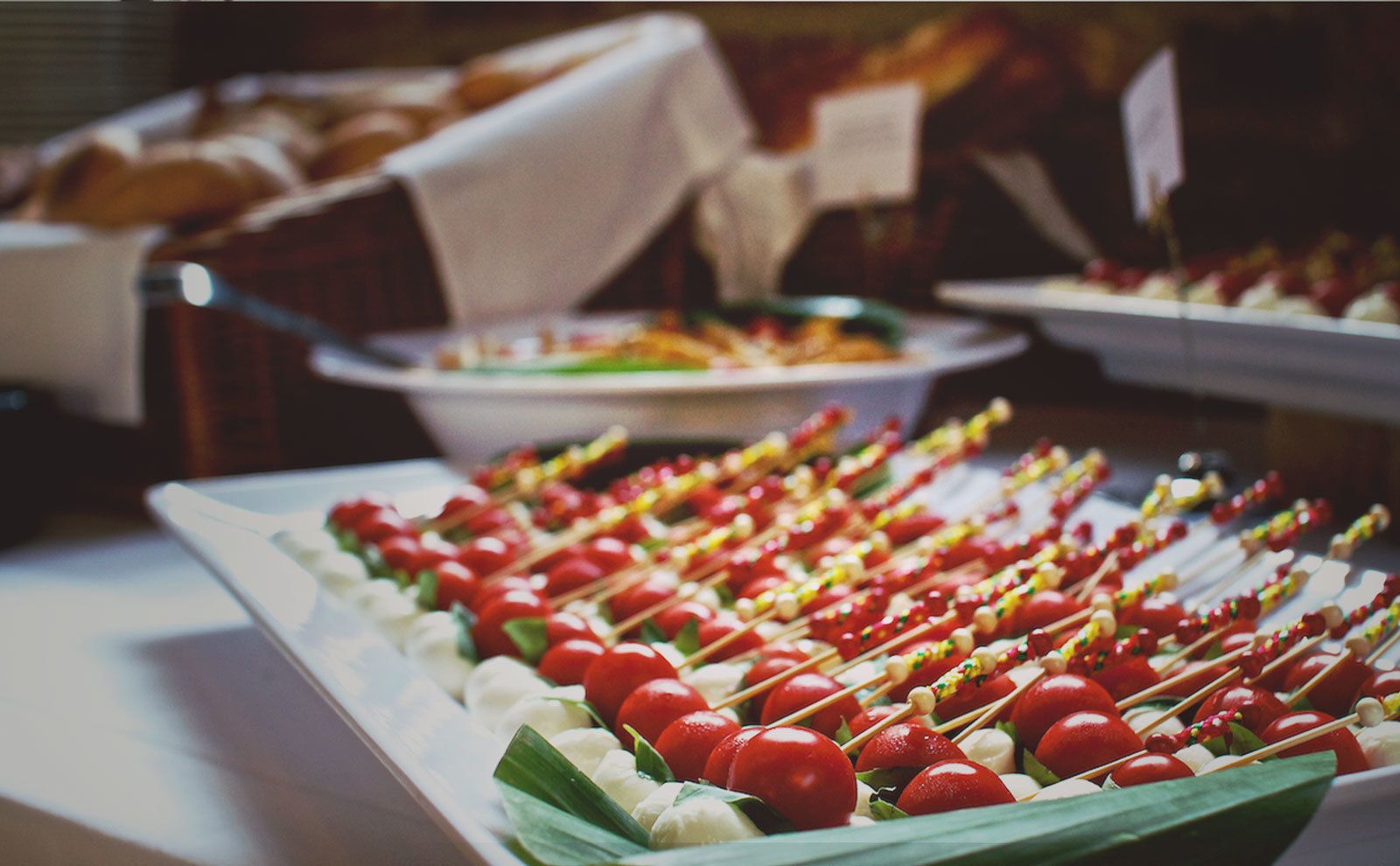 A buffet with various food items, including skewers with cherry tomatoes and mozzarella balls.