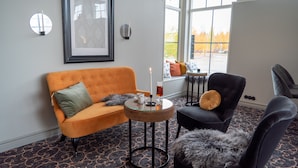 A modern living room with a sofa, armchair, and round coffee table. - Orsa Järnvägshotell (Orsa)