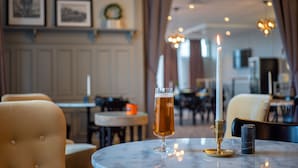 A table with a glass of beer, a candle, and a marble coaster in a restaurant setting. - Orsa Järnvägshotell (Orsa)