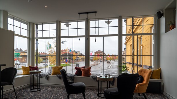 A room with large windows, a black and yellow patterned carpet, and two chairs with cushions. - Orsa Järnvägshotell (Orsa)