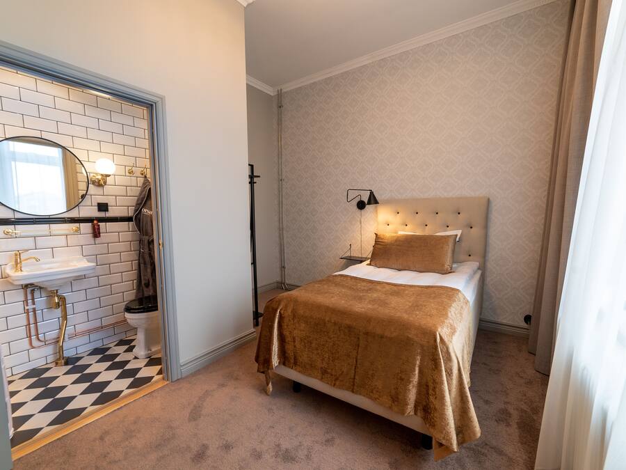 Et soveværelse med en seng, sengetæppe, natbord og et spejl.
