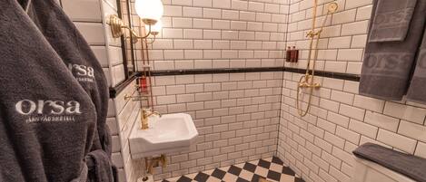 A bathroom with a checkered floor, a white sink, and a shower with gold fixtures.