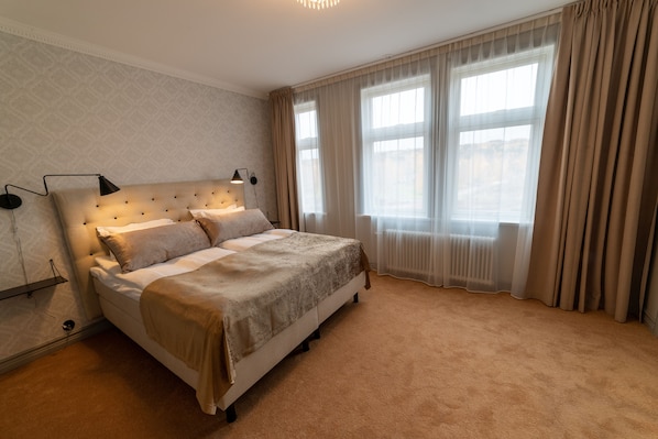 A neatly arranged bedroom with a large bed, a bedside lamp, and a window with curtains. - Orsa Järnvägshotell (Orsa)