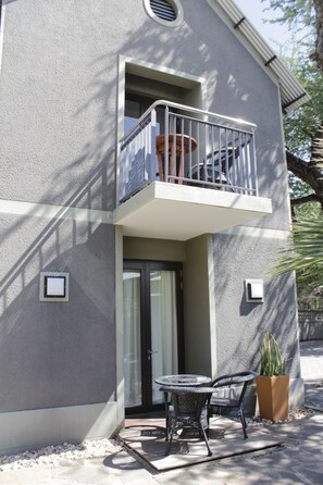 Un edificio de dos pisos con balcón, una puerta y un pequeño espacio al aire libre con mesa y sillas.