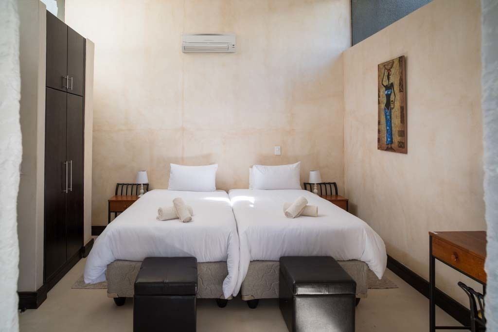 A double room with two beds, a wardrobe, a desk, and a painting on the wall.