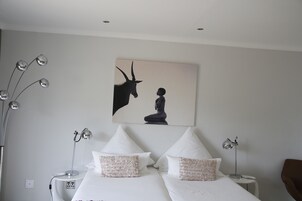 Habitación de hotel con dos camas, un cuadro grande de un caballo y un niño, y lámparas modernas.