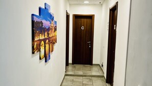 A hallway with a tiled floor, a door with a 'C' sign, and a wall-mounted artwork depicting a cityscape. - Grandis Rooms (Rome)