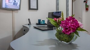 A modern office with a curved desk, a laptop, a smartphone, a framed certificate, and a television displaying a room. - Grandis Rooms (Rome)