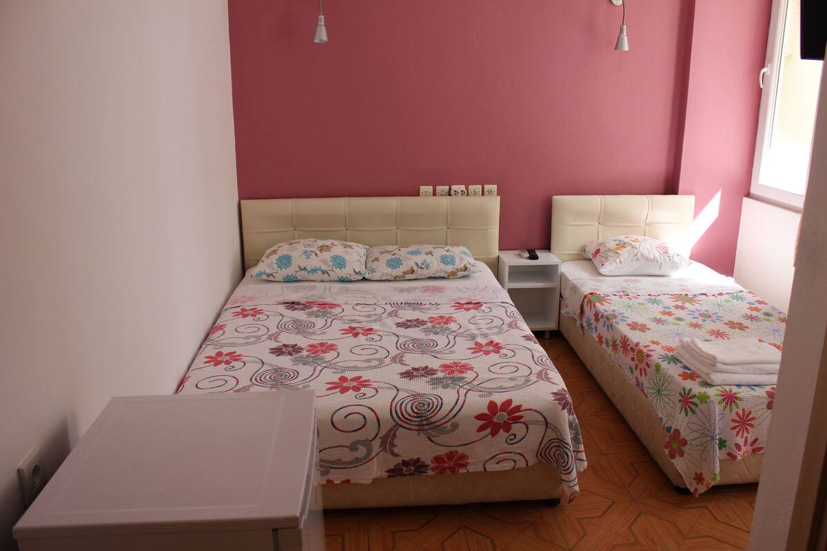 A bedroom with two beds, a bedside table, and a wardrobe.