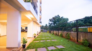 A hotel courtyard with a paved walkway, potted plants, and a stone wall. - Stay At (Bengaluru)