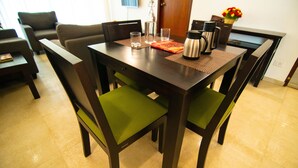 A dining area with a wooden table, four chairs, and a vase of flowers. - Stay At (Bengaluru)