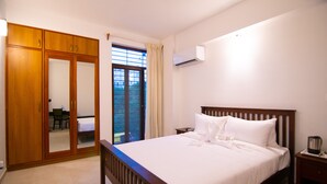 A bedroom with a wooden bed, a wardrobe, a desk, and a window with curtains. - Stay At (Bengaluru)