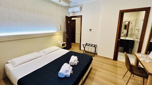 A hotel room with a bed, a desk, and a mirror.