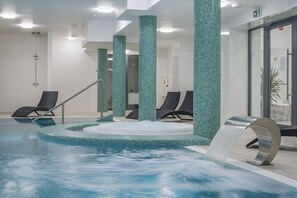 A modern indoor pool with a hot tub, lounge chairs, and a water feature. - Henryk (Swinoujscie)