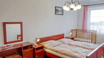 Een slaapkamer met een houten bed, nachtkastjes, een bureau, een spiegel en een raam met gordijnen.