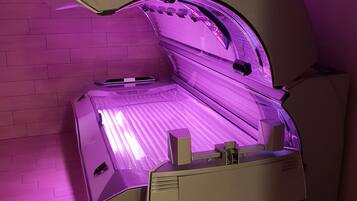 Una cama bronceadora con diseño curvo, un panel de control y reposapiés.