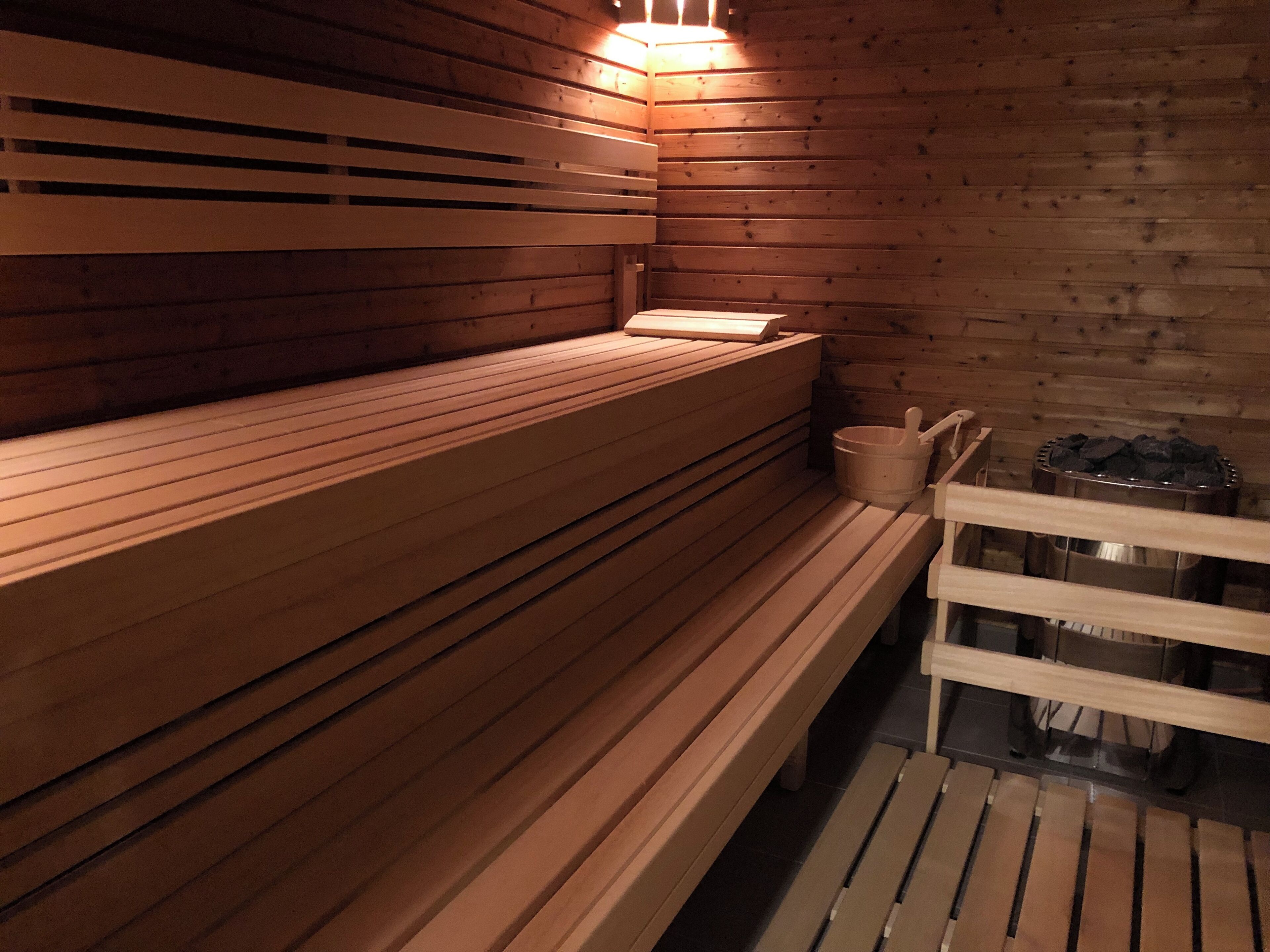Un banc en bois dans un sauna, avec un banc situé sur le côté droit et un mur en bois.