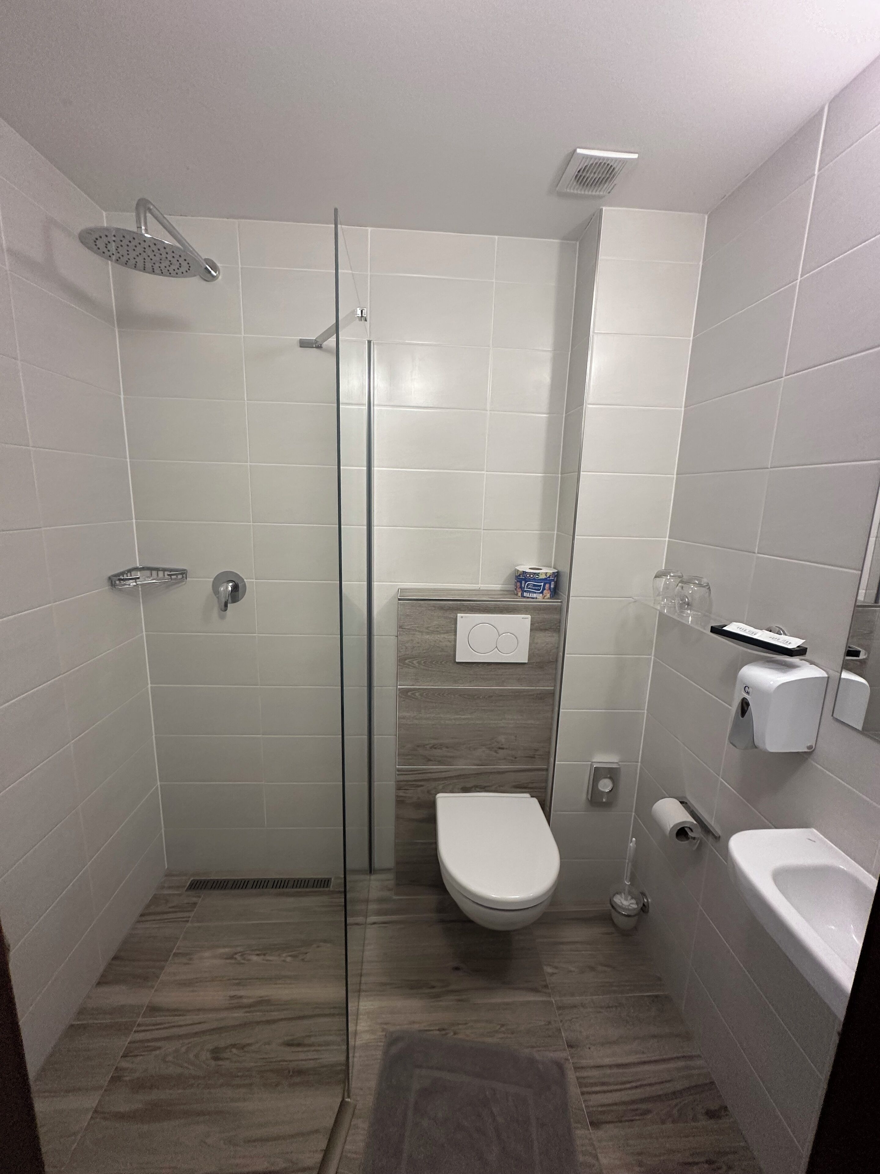 A modern bathroom with a glass-enclosed shower, a toilet, a bidet, and a bathtub.