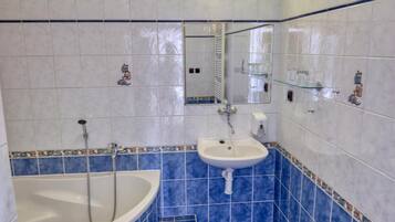 Un baño con bañera, lavamanos y espejo.