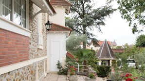 A courtyard with a brick wall, a white door, and potted plants. - Le Colombier (Neuilly-Plaisance)