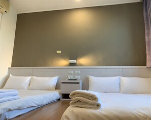 Habitació d'hotel amb dos llits, una taula de nit i una làmpada de paret.